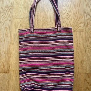 Randig tygväska från Indiska - Färgglad shoppingväska från Indiska med randigt mönster i rosa, vinrött, beige, blått och grönt. 