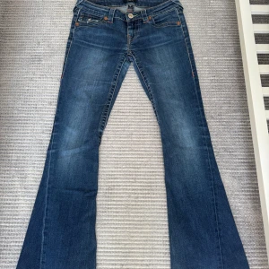 True Religion Joey Low Rise Flare Jeans - Snygga True Religion Joey-jeans i storlek W25, low waist och uppkortade till längd 30. Tyvärr har de blivit för korta för mig, de passade perfekt när jag var runt 160 cm. Uppkortade hos Jonells skräddare (se sista bild för jämförelse, mina LTB är också längd 30).  Billigt pris eftersom de är uppkortade och har lite slitage nertill (se bild 4). Hör av dig privat för fler bilder då alla inte fick plats här.