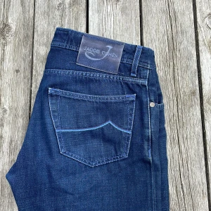 Jacob Cohen jeans, 622 - Snygga blå jeans från Jacob Cohen med klassisk femficksdesign och coola blå sömmar. Jeansen har knappar i metall och unika detaljer på insidan, samt en patch med logga bak. Handgjorda i Italien och tillverkade i mjukt jeansmaterial. Längd 104 bredd 42! Modellen är Bard 622! Notera att den aldrig blivit tvättade!