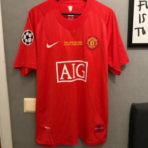 Manchester United Ronaldo 7  - Säljer en röd Manchester United fotbollströja från Champions League-finalen 2008 med Ronaldo 7 på ryggen. Tröjan har korta ärmar, AIG som sponsor på bröstet och broderat klubbmärke. Materialet är lätt och andas, perfekt för match eller samling. Replika!!!