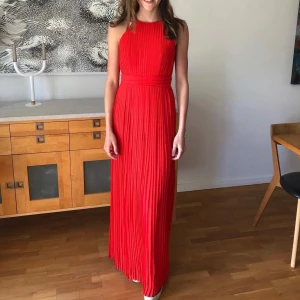Röd plisserad långklänning - Röd plisserad långklänning med markerad midja från Asos i storlek 38. Endast använd en gång, så i jättefint skick! Kan självklart skicka fler bilder💕