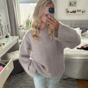 Ljuslila stickad tröja  - Supermysig ljuslila stickad tröja från Lindex med breda, ribbade muddar och rund hals. Tröjan är bara prövad, nypris 1499kr. Materialet är fluffigt och mjukt trots att den är i ull