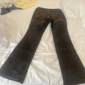 Bootcut jeans från H&M Divided, svart - Svarta bootcut jeans från H&M Divided i storlek 38. Snygga kontrastsömmar i gult och klassisk femficksdesign. Jeansen har en bredare benvidd nedtill och är tillverkade i jeansmaterial med en mörk tvätt. Perfekta för dig som gillar retrovibe och cool siluett.