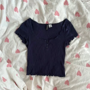 Mörkblå croppad topp - Supersöt mörkblå croppad topp från H&M Divided med ribbad struktur, spetskant vid halsringningen och tre knappar framtill (enbart dekoration). Kortärmad med vågig kant på ärmar och nederkant!💞                                                  
