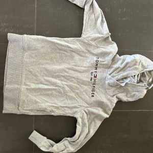 Grå hoodie från Tommy Hilfiger 140 - Snygg grå hoodie från Tommy Hilfiger med klassisk logga tryckt på bröstet. Storlek 140