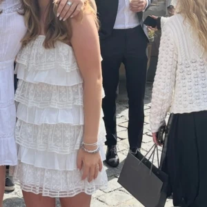 Vit volangklänning  - Supersöt vit miniklänning med tunna axelband och flera lager volanger. Andvänd en gång, nyskick.