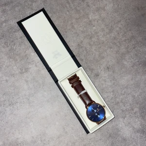 Blå klocka från Black Oak med läderband - Stilren klocka från Black Oak med djupblå urtavla, guldiga detaljer och två mindre urtavlor. Klockan har ett brunt läderarmband som ger en klassisk vibe. Perfekt accessoar för dig som vill sticka ut med en snygg och modern look.