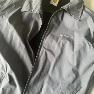 Grå jacka från Carhartt - Snygg grå vindjacka från Carhartt, bra skick! Storlek S/M,  jag är 180/normalbyggd och den har smal passform.