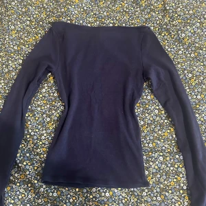 Mörkblå långärmad topp från Gina Tricot - En mörkblå långärmad topp från Gina Tricot. Modellen är figurnära med rak halsringning och är tillverkad i mjuk bomull. Perfekt att styla med jeans eller kjol för en enkel och stilren look. Användt få gånger. 