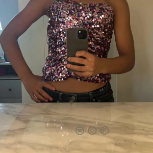 Rosa paljettprydd tubtopp - Säljer en glittrig rosa tubtopp täckt med paljetter. Toppen är ärmlös och perfekt för en festlig kväll. Den har en tight passform och ger en snygg look. ( liten i storlek)