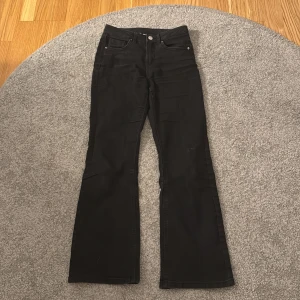 Svarta bootcut jeans från Kappahl - Svarta jeans från Kappahl i modell med bootcut. Klassisk femficksdesign och normal passform. Perfekta svarta byxor med lite utsvängda ben för en trendig look.