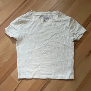Vit t-shirt från H&M Divided - En basic vit t-shirt från H&M Divided. Modellen är enkel med rund halsringning och korta ärmar. Ganska kort/croppad