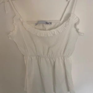 Vit volangprydd topp från 157 - Säljer en söt vit linnetopp från 157 som inte kommer till användning längre. Perfekt för varma dagar!💗
