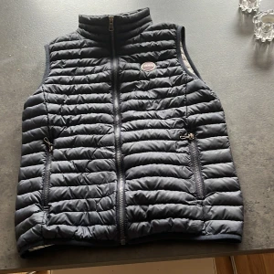 Marinblå dunväst från Colmar - Snygg marinblå dunväst från Colmar med dragkedja och två praktiska fickor framtill. Västen har en quiltad design och en hög krage för extra värme. Perfekt för kyliga dagar när du vill hålla stilen.