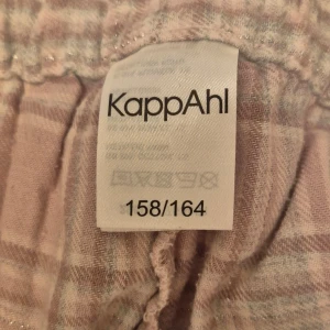 Rosa och grå rutiga byxor från KappAhl - Mysiga byxor från KappAhl i rosa och grått/grönt/rosa rutit mönster. Perfekta för att chilla hemma eller som pyjamasbyxor. Aldrig använda bara provade💕 skriv för frågor💕