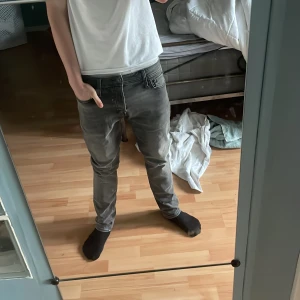 Grå slim fit jeans - Säljer ett par grå slim fit jeans med klassisk femficksdesign och dragkedjegylf. Jeansen har en något tvättad look och raka ben. Perfekta för dig som gillar en stilren och enkel vardagsstil.