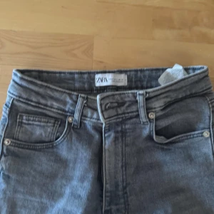 Grå  jeans från Zara - Säljer ett par grå jeans från Zara med slitningar på båda knäna och råa benslut. normal passform. hör av vid frågor 🌸