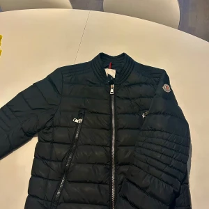 Svart pufferjacka från Moncler(Moncler Amiot) - Säljer en svart jacka från Moncler. Jag har haft jackan i drygt ett år och använt med försiktighet. Jackan har inga defekter förutom serie tidningen som fallit av. Kontakta mig vid frågor🙌