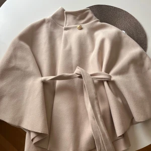 Beige poncho kappa - Säljer den populära Blair ponchon från missäy, helt ny. Jag säljer den endast så den tyvärr inte passade så bra på mig. Den har en guldknapp uppe vid halsen och ett fint mjukt material. Säljer för priset jag köpte den för + frakten jag fick betala. Skriv om ni har några frågor🥰