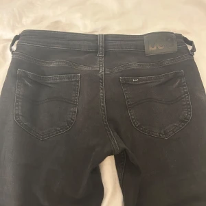 Svarta bootcut jeans från Lee - Säljer ett par svarta low bootcut jeans från Lee, modell Jessica (W26 L31). Säljer dem då dem tyvärr inte kommer till användning. Dem är endast använda 2 ggr!! Hör av dig vid fler frågor💕