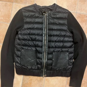 Svart pufferjacka från Massimo Dutti - Säljer en svart pufferjacka från Massimo Dutti med quiltad framsida, dragkedja och två stora fickor i skinnimitation. Ärmarna är i ett mjukare tyg och jackan har en stilren, enkel design. Perfekt för kyligare dagar.