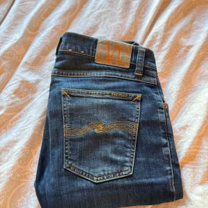 Mörkblå jeans från Nudie Jeans - Tja! Säljer ett par nudie jeans i en marinblå färg extremt snygga med fina slitningar. Skada finns ganska stor men går att fixa Storlek 30/32 (nudie jeans helt klart bäst i gamet)✌️💫❤️