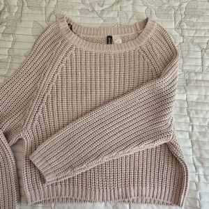 Beige/Dammrosa stickad tröja från H&M - Mysig beige rosa stickad tröja från H&M med grovstickat mönster och rund halsringning. Tröjan har långa ärmar och en något croppad passform, perfekt för lager på lager under kyliga dagar. Sitter jätte fint och använd endast en gång! 