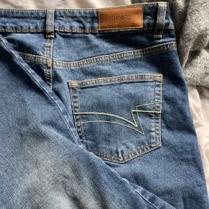 Blå jeans från Junkyard - Säljer ett par klassiska blå jeans från Junkyard med snygga kontrastsömmar och bakficka med unik sömdesign. Jeansen har normal passform och är perfekta till vardagslooken. Har bara provat så dom är andvänat 1 gång 