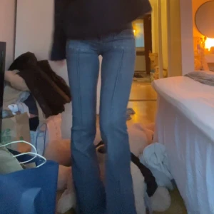 Blå bootcut jeans med markerade sömmar - Säljer ett par blå bootcut jeans med markerade sömmar längs benen och klassiska fickor fram och bak. Jeansen har låg midja och stängs med dragkedja och knappar. Samma modell som på första bilden, med jeans material istället bara. De är en nagellacks fläck på framsida ben, därav priset