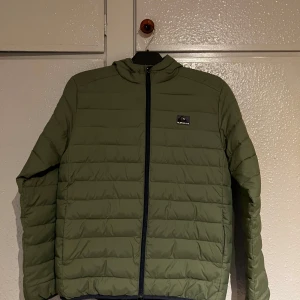 Grön quiltad jacka från Quiksilver - Säljer en snygg grön quiltad jacka från Quiksilver. Jackan har en dragkedja framtill och är långärmad. Perfekt för kyligare dagar med sin stilrena design och bekväma passform.