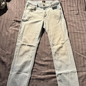 Ljusblå jeans från Lee - Säljer ett par ljusblå jeans från Lee med klassisk femficksdesign och knappgylf. De har en rak passform och är perfekta för en avslappnad stil. Midjan är W29 och längden L32. Riktigt snygga men tyvärr för små i midjan på mig. 