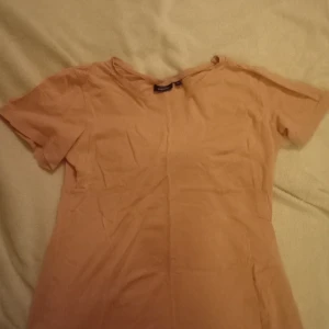 Beige t-shirt från Kappahl - Säljer en enkel och stilren beige t-shirt från Kappahl. Perfekt basplagg med korta ärmar och rund hals. Passar till många olika outfits och tillfällen.