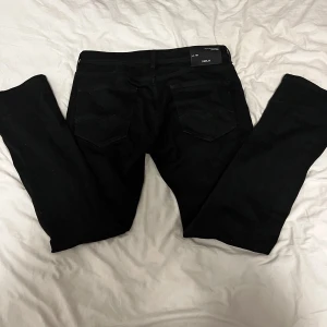 Svarta jeans från Replay - Snygga svarta jeans från Replay med klassisk femficksdesign. Jeansen har en stilren look med diskreta sömmar och en bekväm passform. Perfekta för en stilren vardagsoutfit. Pris kan diskuteras. Haft på mig dom 1 gång men säljer för att de är lite för stora