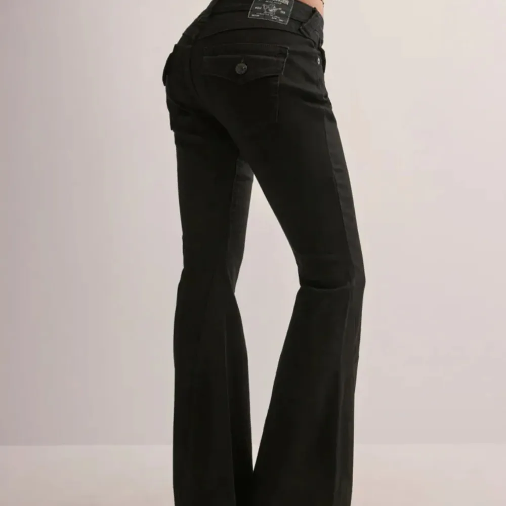 Snygga svarta bootcut jeans från True Religion med klassiska femficksdetaljer och knappstängning. Jeansen har en stilren design med märkets logga på bakfickan och en bekväm passform.. Farkut & Housut.