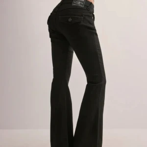 Svarta bootcut jeans True Religion - Snygga svarta bootcut jeans från True Religion med klassiska femficksdetaljer och knappstängning. Jeansen har en stilren design med märkets logga på bakfickan och en bekväm passform.
