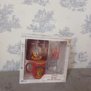 Harry Potter Gryffindor presentset - Säljer ett Harry Potter presentset med Gryffindor-tema. Setet innehåller en röd mugg med Gryffindor-vapenskölden och ett glas med samma emblem. Perfekt för fans av Harry Potter-serien! 🧙‍♂️