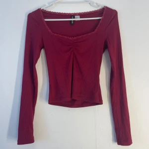 Röd ribbad topp med spetsdetalj - Säljer en snygg röd ribbad topp med långa ärmar och spetsdetalj vid halsringningen från H&M. Har använt 2-3 gånger