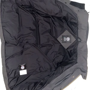 Grå dunjacka från Canada Goose - Säljer en grå dunjacka från Canada Goose med avtagbar huva och knappar framtill. Jackan har en quiltad design och långa ärmar, perfekt för kalla dagar. Den är både stilren och funktionell, med flera praktiska fickor. Passar perfekt för vinter.