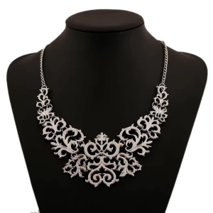 Silverfärgat halsband med dekorativt mönster - Elegant silverfärgat halsband med ett intrikat och dekorativt mönster. Perfekt för att ge en stilfull touch till din outfit. Kedjan är av medellängd och smycket har en vacker, detaljrik design.