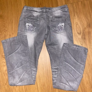 Grå bootcut jeans - Snygga grå bootcut jeans med broderade detaljer på bakfickorna. De är lågmidjade och är lite glittriga🫶 midjemått: 38cm och innerbenslängd: 78cm