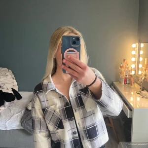 Rutig jacka från KappAhl - Säljer en rutig jacka från KappAhl i svart och beige. Jackan har en klassisk krage och knappar. Storkek 170-XS-S
