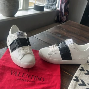 Valentino Rockstud Untitled sneakers - Snygga vita Valentino Rockstud Untitled sneakers med svarta detaljer och  nitar. Från dhgate!!!‼️Aldrig använda, bra kvalité. Säljes då de var för breda för mina fötter❤️‍🔥