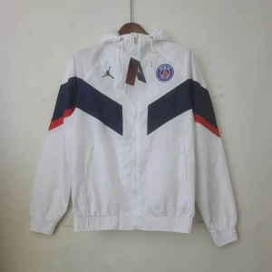 Vit vindjacka från Jordan x PSG - Säljer en snygg vit vindjacka från Jordan x PSG med blå och röda detaljer. Jackan har en dragkedja framtill och en huva med snörning. Perfekt för sportiga tillfällen eller som en stilren vardagsjacka.