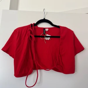 Röd croppad topp  - Röd croptop med snören som snuras runt midjan och knyts ihop.
