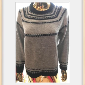 Grå stickad tröja med mönster Esmara - Mysig grå stickad tröja från Esmara med svarta mönstrade ränder över bröst, ärmar och nederkant. Rund halsringning och långa ärmar. Materialet är en blandning av polyakryl, polyester och elastan för extra komfort.