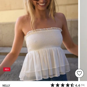 Vit topp från Nelly - Supersöt vit bandeau tubtopp från Nelly med smockad överdel och volangig, luftig nederdel i två lager. Perfekt för varma dagar och ger en romantisk vibe med sin lätta och flowiga känsla. Nyss inköpt och använt 1 gång