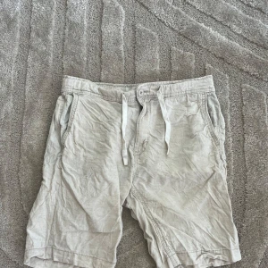 Beige shorts med snörning från Kappahl - Snygga beige shorts från Kappahl i bomull med avslappnad passform. De har elastisk midja med snörning, sidofickor och en bakficka med knapp. Perfekta för varma dagar när du vill ha det chill och bekvämt.