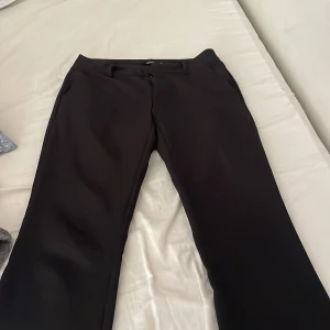 Svarta kostymbyxor med bootcut - Snygga svarta kostymbyxor med bootcut-silhuett och klassiska fickor fram. Vad jag vet så är de inget fel på dom men säljer då jag behöver en annan storlek, hör av er vid intresse eller frågor❤️