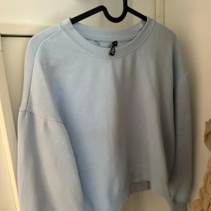 Ljusblå sweatshirt från H&M - Enkel och snygg ljusblå sweatshirt från H&M med rund halsringning och avslappnad passform. Tröjan har långa ärmar och är tillverkad i mjuk bomull, perfekt för chill dagar eller när du vill ha en clean look.