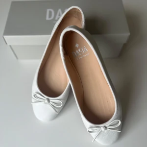 Vita ballerinaskor i skinn från Dasia - Jättefina vita ballerinaskor från Dasia i mjukt skinn. Säljer dessa pga av att de är för stora för mig. Köpte för inte alls längesen och har endast använt 1 gång, så de är precis som nya (därav priset)! De är väldigt sköna då de är i riktigt skinn och verkligen superfina nu till sommaren!